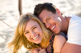 a blonde woman and a brunet man smiling